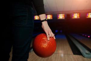 mano dell'uomo giocatore con braccialetto che tiene palla da bowling foto