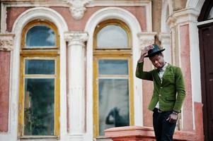 ritratto di moda di uomo afroamericano nero su giacca di velluto verde rimanere sulle scale e indossare il suo cappello nero sfondo vecchio palazzo. foto