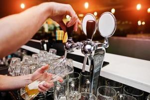 primo piano della mano del barman al rubinetto della birra foto