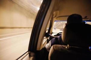 vista dal finestrino dell'auto, auto che si muove attraverso il tunnel alla luce. autista che guida l'auto foto