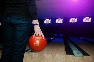 mano dell'uomo giocatore con braccialetto che tiene palla da bowling foto