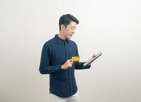 Ritratto di giovane uomo asiatico in possesso di carta di credito e tablet foto