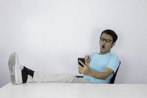 il giovane asiatico arrabbiato si arrabbia quando chiama sullo smartphone. uomo indonesiano che indossa una camicia blu. foto