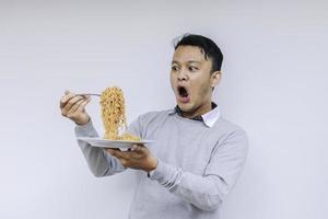 ritratto di shock e wow il giovane asiatico si diverte con i noodles. mangiare il concetto di pranzo. foto