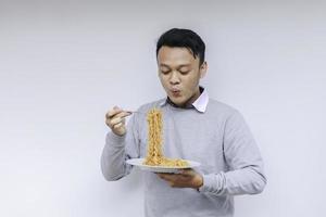 il giovane uomo asiatico si diverte con le tagliatelle. mangiare il concetto di pranzo foto