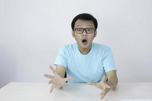 wow e faccia scioccata del giovane asiatico con il gesto della mano aperta. concetto di modello pubblicitario con camicia blu. foto