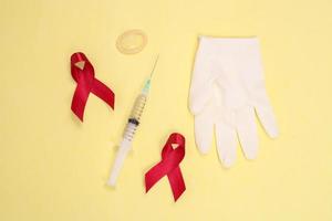 nastro rosso e simbolo del dispositivo medico contro l'hiv isolato su sfondo giallo foto