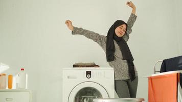 la donna asiatica in hijab si rilassa dopo aver lavato i vestiti a casa foto