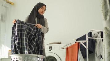 donna asiatica in hijab che asciuga il bucato a casa foto
