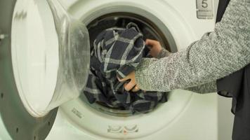 donna asiatica in hijab che lava i vestiti in lavatrice a casa foto