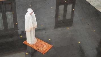 donna musulmana asiatica che prega da sola senza imam nella moschea foto