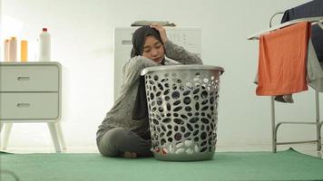 donna asiatica stanca in hijab che lava i vestiti a casa foto