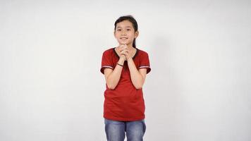 bambina asiatica che elemosina un desiderio sorridente su sfondo bianco isolato foto