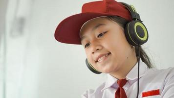 ragazza asiatica della scuola elementare che studia felicemente online a casa foto