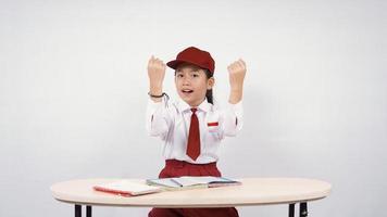 ragazza asiatica della scuola elementare che studia con successo isolata su fondo bianco foto