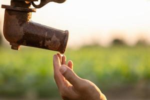 mano del contadino in attesa di acqua dalla pompa dell'acqua esterna vintage. per il concetto di stagione di siccità foto