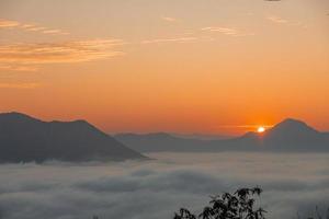 la nebbia del mare e l'alba dorata coprono l'area sulla cima della collina doi phu thok, chiang khan, loei, tailandia con lo sfondo dell'alba in inverno. foto