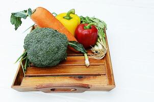 verdure miste su cesto di legno con broccoli e carote con peperoncino e cipolla foto