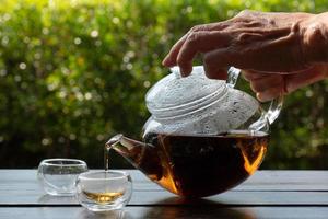 il tè caldo veniva versato in un bicchiere servito sul tavolo della caffetteria foto