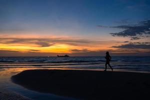 silhouette di donna che lavora correndo sulla spiaggia al tramonto foto
