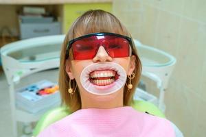 paziente felice di odontoiatria sulla sedia con gli occhiali foto