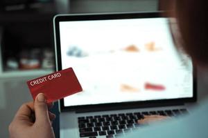 concetto di shopping online con la mano della donna che utilizza il laptop e cerca la carta di credito per il prodotto dell'ordine di acquisto a casa. foto