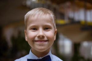 ritratto di un ragazzo in camicia bianca e papillon nero, sorridente scolaro allegro foto