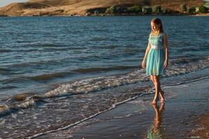 ragazza carina che cammina sulla spiaggia in estate foto