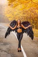 bella donna con le ali nere nella foresta d'autunno foto