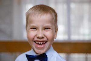 ritratto di un ragazzo in camicia bianca e papillon nero, sorridente scolaro allegro foto