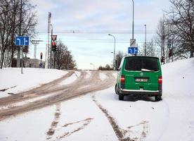 vilnius lituania 26 dicembre 2021 auto verde in piedi su strada innevata con segnaletica stradale, alberi e fili sul cielo blu foto