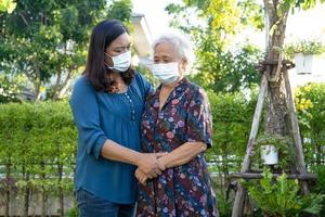 il caregiver aiuta la donna anziana asiatica mentre cammina con felice nel parco naturale. foto