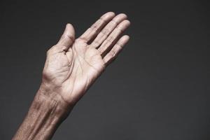 primo piano delle mani di una persona anziana su sfondo grigio foto