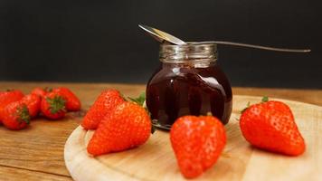 marmellata di fragole nel barattolo di vetro con frutti di bosco freschi su fondo di legno foto