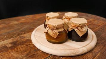 quattro vasetti di vetro con diversi tipi di marmellata su tavola di legno. marmellata fatta in casa foto