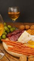 spuntini per il vino. piatto di carne e formaggio. salsicce, formaggio, noci, uva, cracker foto