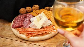 primo piano sfocato con la mano che tiene un bicchiere di vino. tagliere di formaggi e carne foto