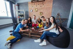 gruppo di amici creativi seduti al tavolo di legno. persone che si divertono mentre giocano a giochi da tavolo foto