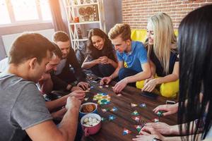 gruppo di amici creativi seduti al tavolo di legno. persone che si divertono mentre giocano a giochi da tavolo foto