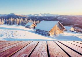 paesaggio montano invernale con una foresta innevata e una capanna di legno foto