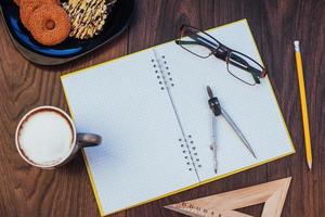 vista dall'alto di taccuino, cancelleria, strumenti di disegno e alcune tazze di caffè. foto