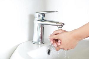 lavarsi e strofinarsi le mani sul lavandino con acqua di rubinetto argentata foto