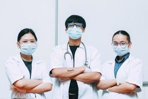 gruppo di medici che indossano maschera protettiva e uniforme in posa con sicurezza foto