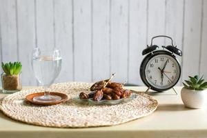 bicchiere di acqua potabile e date con sveglia a ore 6. ramadan tradizionale, concetto di tempo iftar foto