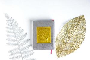 oro arabo sul libro del sacro Corano con foglie d'argento e d'oro su sfondo bianco, bandung indonesia, marzo 2021 foto