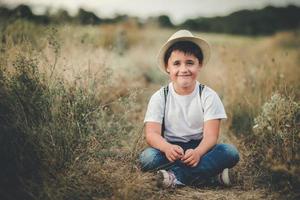 bambino felice seduto nel campo foto