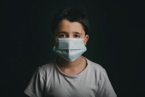 coronavirus, bambino triste che indossa una maschera medica foto