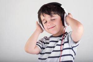 bambino che ascolta la musica con le cuffie foto