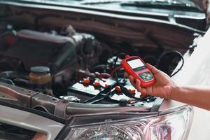 meccanico che utilizza il misuratore di prestazioni della batteria dell'auto foto