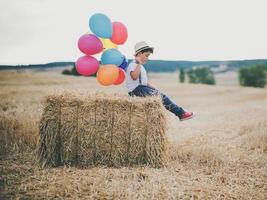 bambino con palloncini nel campo di grano foto